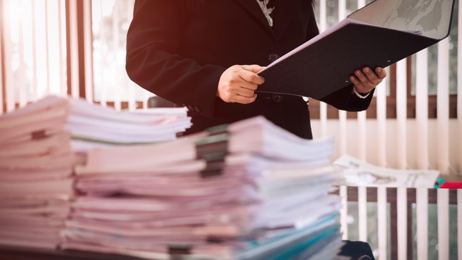 Person holding a file and reviewing documents on a desk.